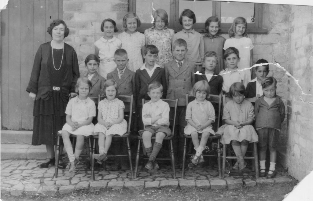 1933 Schoolchildren with teacher Mrs Alice Bulley. Back row: ?; Mary Goring; Joan Goring; Olive Goodenough; Joan Smith; Cowdray. Middle row: ?; Leslie Rumming; ?; Robert Smith; Henry Goodenough; Jesse Fell; ?. Front row: Sybil Smith; ?; ?; ?; Phyllis Goodenough; Babe Cook.